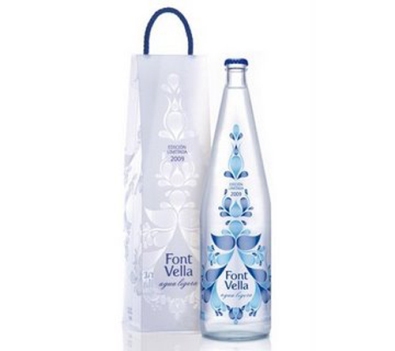 Gotas de agua estilizadas de diferentes tamaños y tonalidades de azul envuelven la botella creando una sutil sensación de movimiento